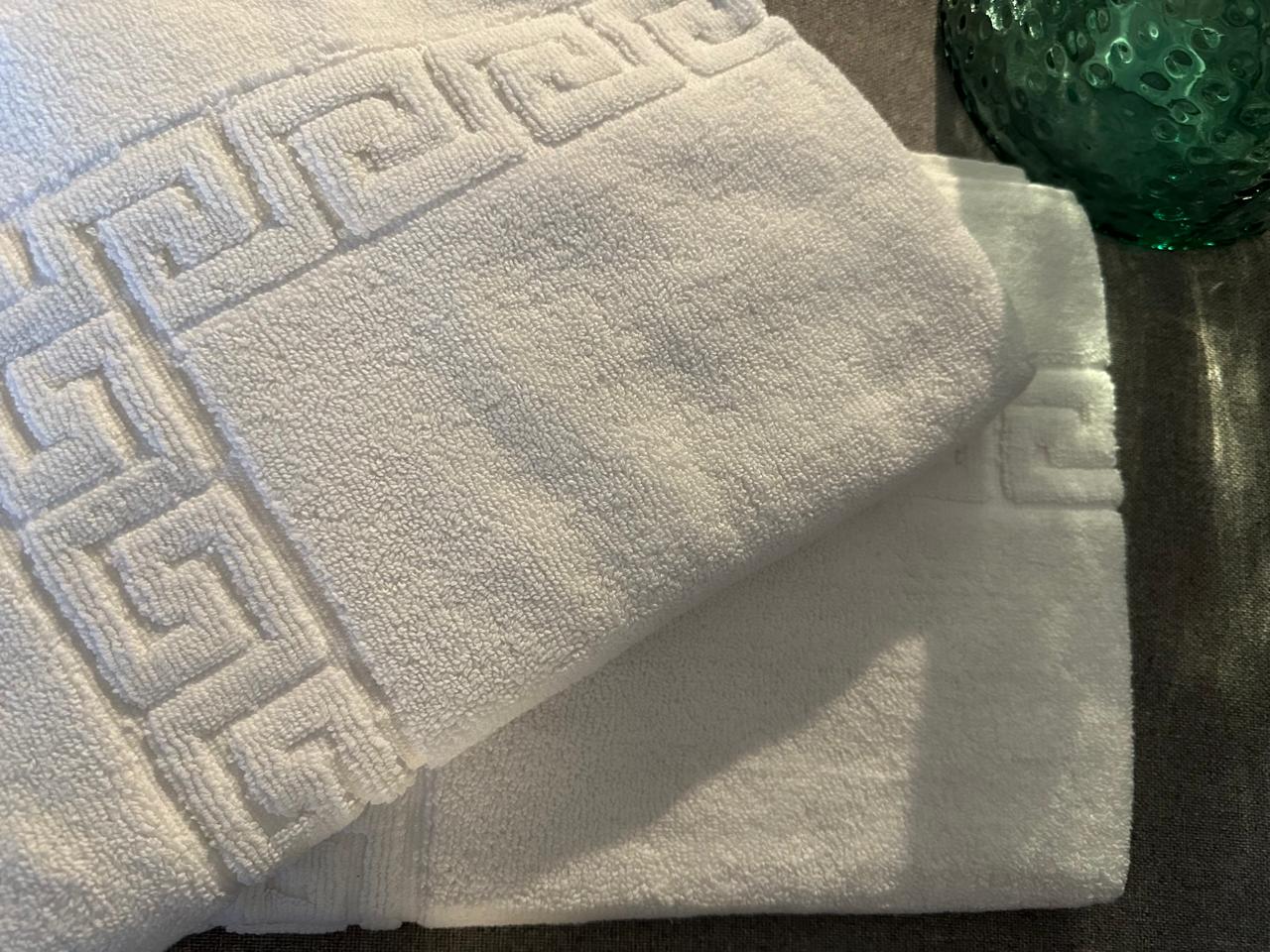 White towel with Greek key pattern on a dark surface